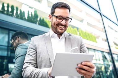 Genç işadamı, bina şirket önünde tablet kullanma.