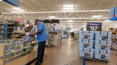 Centerville, Ga / USA - 07: 25: 20: Walmart müşterisi yüz maskesi takarak cam bir kutuda nesnelere göz atıyor