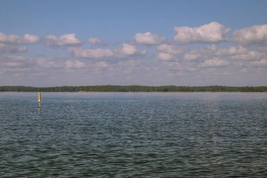 Rüzgarlı bir günde mavi gökyüzü ve bulutlarla göl manzarası