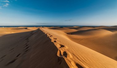 Bir ayak izinin çizildiği kumulun tepesinden maspalomas plajı (Gran Canaria) manzarası. seyahat fotoğrafçılığı. manzara