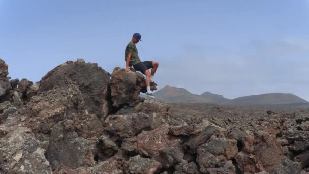 Jovem Desce Topo Uma Rocha Lava Depois Contemplar Paisagem Vulcânica — Vídeo de Stock