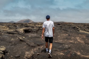 Genç adam Timanfaya Ulusal Parkı 'nda yanmış toprakta yürüyor. Lanzarote. Kanarya Adaları