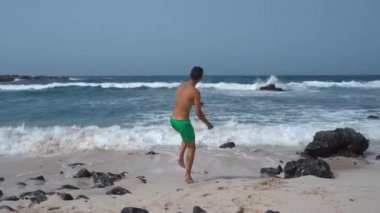 Genç adam plajın kıyısında oynar. Orzola. Lanzarote. Las Palmas. Kanarya Adaları