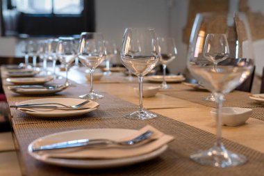 Bardakları ve çatal bıçakları olan birçok restoran masası.