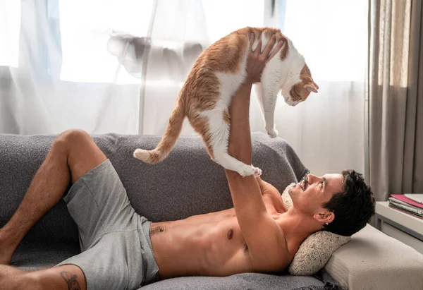 Joven Acostado Sofá Juega Con Gato Blanco Marrón Mientras Sonríe — Foto de Stock