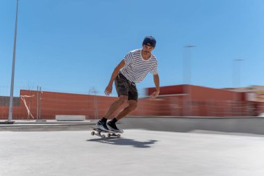 Genç adam güneşli bir günde kaykay havuzunda kayıyor.