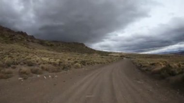 Neuquen, Patagonya Arjantin Varvarco Aguas Calientes rota Timelapse. Vadiler, yatay Altiplane. Otlak ve bulutlu karanlık gri soğuk bir gün bozkırda. Çakıl yalnız yol.
