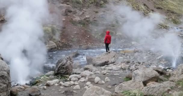 在爆破间歇泉 洛杉矶 Tachos Covunco 暖河之间的岩石红色夹克的妇女 蒸汽在人周围上升 Domuyo 火山的环境 内乌肯省 巴塔哥尼亚 — 图库视频影像