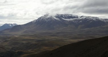 Domuyo volkan gri bir gün kar ile. Kamera hala manzara filme kalır. Otlaklar ve önünde dağlar vadiler. Neuquen, Patagonia, Arjantin