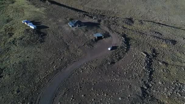 Bâtiments et maisons abandonnés au milieu de la steppe sauvage. Van avec une remorque, au parc national de tromen, Patagonie Argentine. Scène aérienne de drone de vue de dessus, se déplaçant vers le bas. Coucher de soleil heure dorée 