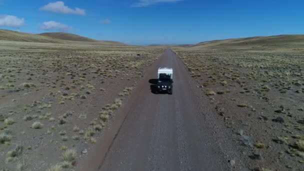 空中无人机场景的面包车和拖车 旅宿汽车在草原 巴塔哥尼亚阿根廷骑在一个砾石偏僻的道路 Tromen 火山国家公园 摄像头移动倒车跟踪车 — 图库视频影像