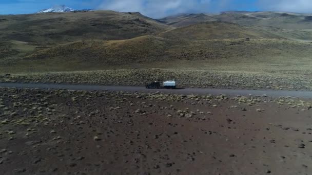 空中无人机现场的面包车和拖车 旅宿汽车在草原 巴塔哥尼亚阿根廷 Rideing 在一个砾石偏僻的道路上 Tromen 火山的背景 国家公园 相机向左移动向上跟踪车 — 图库视频影像