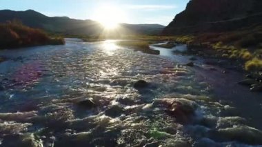 Rüzgarlı bir gün, arka ışık parlama ile gün batımı, altın saatin nehirde barrancas hava dron sahne. Bu nehir Neuquen Mendoza Arjantin gelen durumunu böler. Fotoğraf makinesi Nehri.