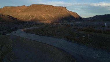 Hava dron. Barrancas Nehri, altın saat, rüzgarlı gün batımında. Neuquen Mendoza, Arjantin böler. Hareketli arka plan, eski köprü inşaatı üzerinden geçen iletir. Gölgede yarım manzara