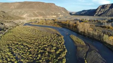 Barrancas Nehri, altın saat, rüzgarlı gün batımında hava dron sahne. Nehir Neuquen - Mendoza Arjantin devlet böler. Arka plan, eski köprü inşaatı. Kamera hareketli ileriye