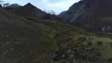 Otlaklar yüksek dağ ve nehir Covunco, arka plan, karlı Domuyo volkan. Yana doğru nehir sonunda keşfetmek hareketli hava dron sahne. Neuquen, Patagonia, Arjantin.
