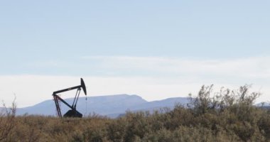 Ayrıntı pompa platformu çalışma ticari sanayi amacı ile petrol çıkarma yukarı ve aşağı hareket. Otlaklar ve arka planda bozkır tepeler. Mendoza, La Payunia, Patagonya Arjantin.