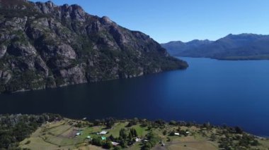Paimun Gölü, Patagonia, Arjantin bazı evler ve bir tekne, ağaçlar, dağlar ve bir kaya duvarı ilerlemeye hava dron sahne