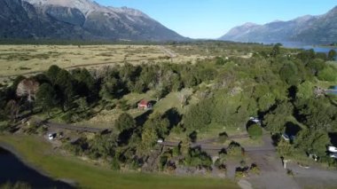 Hava dron dağlar, ağaçlar ve estepa, Neuquen, Patagonia, Arjantin, Milli Parkı Lanin ilerlemeye Paimun Gölü, toprak yol, araç izleme ve otopark ve evler, kamera sahne,