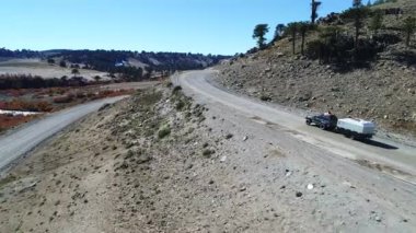 Kamyonet ve karavan Litran Nehri vadisinde bir çakıl yolda seyahat hava dron sahne. Renkli Sonbahar bitki örtüsü. Kamera araba izler. Vasıl geçmiş Araucarias plantation, neuquen Patagonya çam.