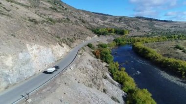 Pulmari nehir kaya, bozkır, dağlar, ağaçlar, yol ve bir izleme van ve yakaladığında bir römork ile hava dron sahne. Kamera hareketli ileriye.