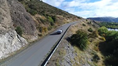 Bozkır, dağlar, ağaçlar ve yol ve bir izleme van ve yakaladığında bir römork hava dron sahne. Kamera hareket iletir. Pulmari Nehri sağ.