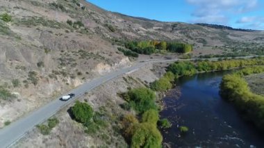 Pulmari nehir kaya, bozkır, dağlar, ağaçlar, yol ve bir izleme van ve yakaladığında bir römork ile hava dron sahne. Kamera hareketli ileriye.