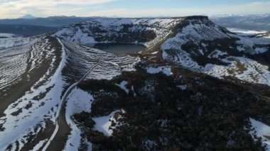 Villa Pehuenia karlı Batea Mahuida volkan hava dron sahne. Kamera geriye doğru hareket eder. Karlı dağlar, renkli orman sahne altında arka plan. Neuquen, Patagonya Arjantin.