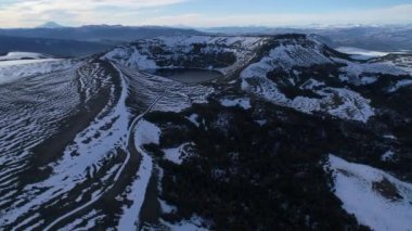 Villa Pehuenia karlı Batea Mahuida volkan hava dron sahne. Kamera iner, Bütün krater ve lagün manzarasına. Karlı Dağları'nın arka plan. Neuquen, Patagonya Arjantin.