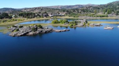 Hava dron sahne kayalar, ağaçlar, araucarias, dağlar ve bozkır Pulmari Gölü. Hareketli kamera iletir ve sonbahar sahile güneşli bir günde yukarı. Biz bir toprak yol ve büyük bir inşaat görebilirsiniz.