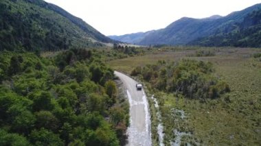Güneşli bir sonbahar karavanda bir kamyonetle ve yeşil ağaçlar, Neuquen, Moquehue, Patagonia, Arjantin ile bozkır ile ıslak toprak yol hava dron sahne