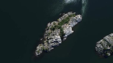 Hava üst Pulmari gölde bir Rock Island ağaçları ile Drone sahne görüntüleyin. Kamera hareket iletir. Güneşin suya yansıyan.