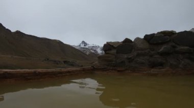 Kaplıcalar Cajon Grande Mendoza Cuyo, Arjantin içinde ilk kişi sahne. Adam su ve kar ile Campanario dağının panoramik görünümü. And Dağları. Turistik yer, doğal sıcak su banyosu.