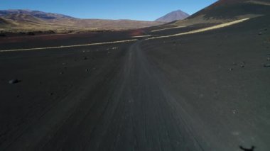 Hava dron sahne olan La Payunia Milli parkta Malargue, Mendoza. Pampa Negras siyah ile kırmızı zemin volkan ve altın otlar desen kayalar. Arka plan üzerinde Payun Liso volkan. Çakıl yol.