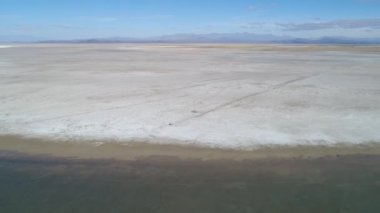Malargue, Mendoza, Arjantin Llancanelo gölünde hava dron sahne. Yansıması ile su, otopark ve beyaz kuru tuzlu shore zemin van. Kamera hareket iletir. Belgili tanımlık Andes dağ zemin üzerine
