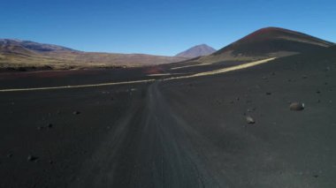 Hava dron sahne olan La Payunia Milli parkta Malargue, Mendoza. Pampa Negras siyah ile kırmızı zemin volkan ve altın otlar desen kayalar. Arka plan üzerinde Payun Liso volkan. Çakıl yol.
