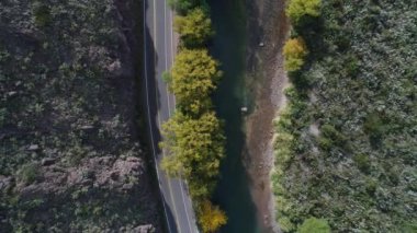 Hava dron sahne üst görüntülemek Atuel nehir, willows ve San Rafael, Mendoza Cuyo Arjantin Caddesi. Yukarı doğru kameranızın ve tarafından geçen motosiklet. Kayalar ve su akan yeşil algler.
