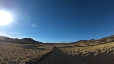 Timelapse, La Payunia Milli parkta Malarge, Cuyo, Mendoza. Çakıl siyah volkanik yol kayalar ve altın otlar üzerinde ilerlemeye araba, kamera kavradı. Volkanlar arka plan üzerinde.