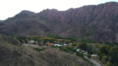 Atuel river canyon San Rafael, Mendoza Cuyo Arjantin hava dron sahne. Yukarı doğru hareket kamera. Willows ağaçlar ve Nehri yanındaki sokak. Küçük bir köy, kasaba büyük dağlar altında.