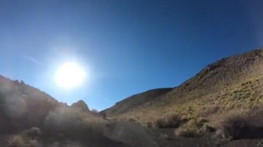 Timelapse, La Payunia Milli parkta Malargue, Cuyo, Mendoza. Çakıl siyah volkanik yol kayalar ve altın otlar üzerinde ilerlemeye araba, kamera kavradı. Payun Liso volkan başında.