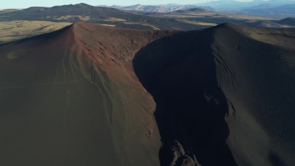 Payunia 国立公園 Malargue メンドーサで溶岩のベッドと黒の壊れた火山火口の空中ドローン シーン カメラ移動転送します 山の斜面上のパス 背景にアンデス山脈 — ストック動画