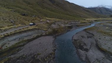 Andes Dağları, Mendoza Cuyo Arjantin hava dron sahne. Patagonya bozkır manzara. Kamera gidiş aşağı ve ileri bir çakıl yalnız yol ve van römork, kamyonet ve karavan ile. Campanario dağın karla arka planda. Bulutlu karanlık d