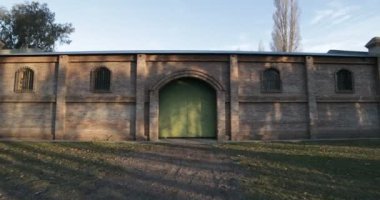 Stabilize kamera hareket büyük tuğla inşaat vasıl günbatımı altın saat. Yeşil kapı, büyük kapı ile bina doğru hızlı hareket kamera. Kiler Mendoza, Arjantin şarap üretimi için.