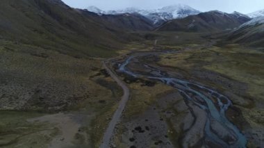Andes Dağları, Mendoza Cuyo Arjantin hava dron sahne. Patagonya bozkır manzara. Aşağıya doğru ve ileri bir çakıl yalnız yol üzerinde kameranızın. Campanario dağın karla arka planda. Bulutlu karanlık gün.