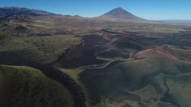 Hava dron sahne olan La Payunia Milli parkta Malargue, Mendoza. Pampa Negras siyah ile kırmızı zemin volkan ve altın otlar desen kayalar. Arka plan üzerinde Payun Liso volkan. Çakıl yol.
