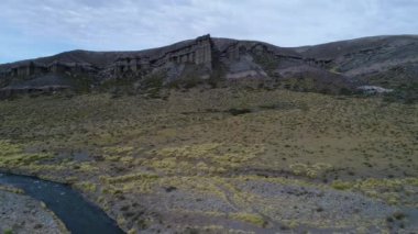 Kaya oluşumları ile kale, evler siluet. Castillos de Pincheira ve nehir pincheira. Hava sahne Nehri aşar ve kaya oluşumları doğru gider. Bozkır manzara. Patagonia, Malargue
