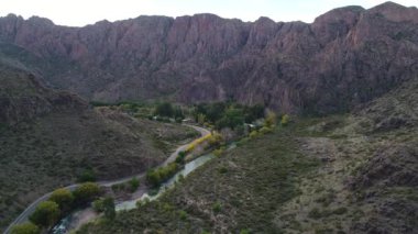 Atuel river canyon San Rafael, Mendoza Cuyo Arjantin hava dron sahne. Kamera hareket iletir. Caddesi söğüt ağaçları ve Nehri yanındaki. Küçük bir köy, kasaba büyük dağlar altında.