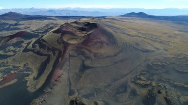 Hava dron sahne olan La Payunia Milli parkta Malargue, Mendoza. Pampa Negras siyah ile kırmızı zemin volkan ve altın otlar desen kayalar. Çakıl yol. Eski volkan üzerinde uçan kamera.