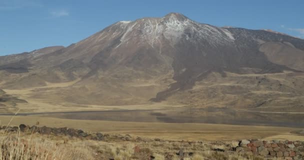 Tromen 国立公園 溶岩の上に雪のベッドと山 反射とラグーン 自然草原と草原の風景 ネウケン アルゼンチン パタゴニア — ストック動画