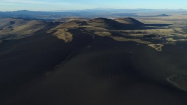 Hava dron sahne La Payunia Milli Parkı Malargue, cuyo, Mendoza, Arjantin'in. Altın otlar ve lapillis kayalar ile karanlık volkan Dağları siyah. Kamera hareketli ileriye.